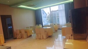 Une salle de conférence équipée de tables et de chaises, de grandes fenêtres et d’un téléviseur.