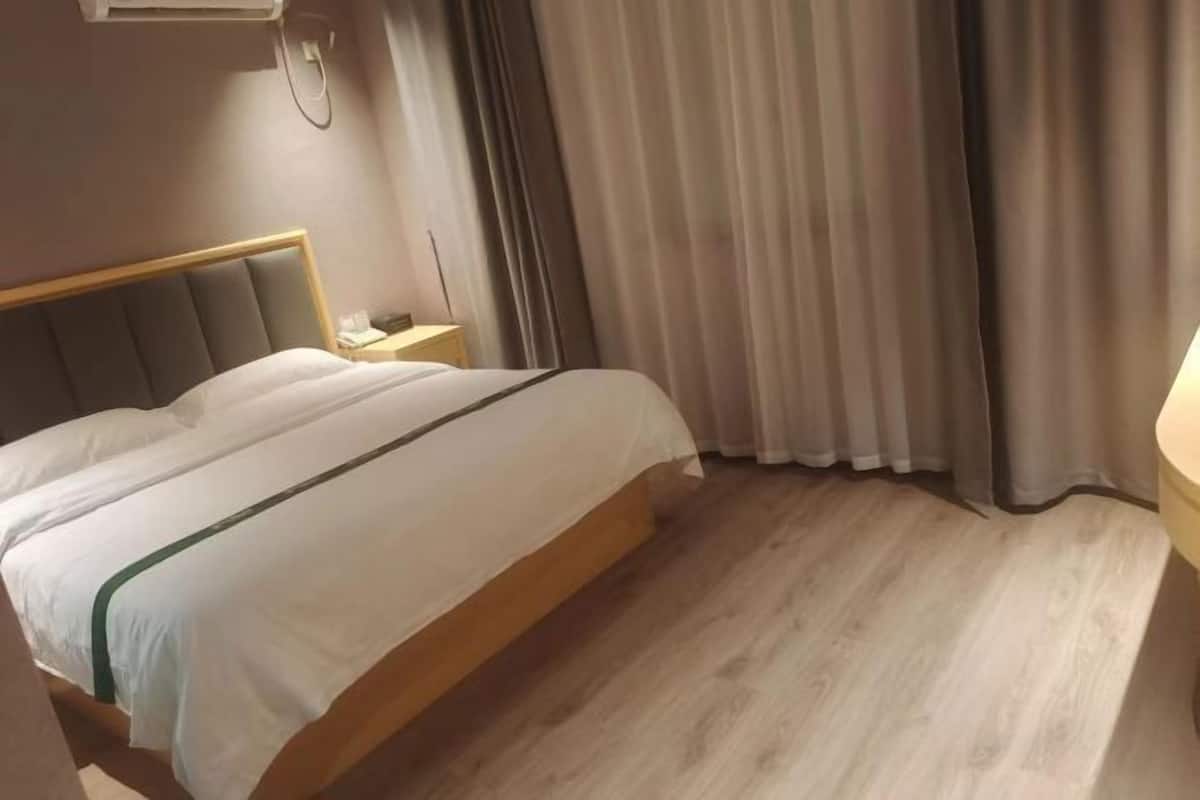 Una camera d'albergo con un letto, un comodino e delle tende.