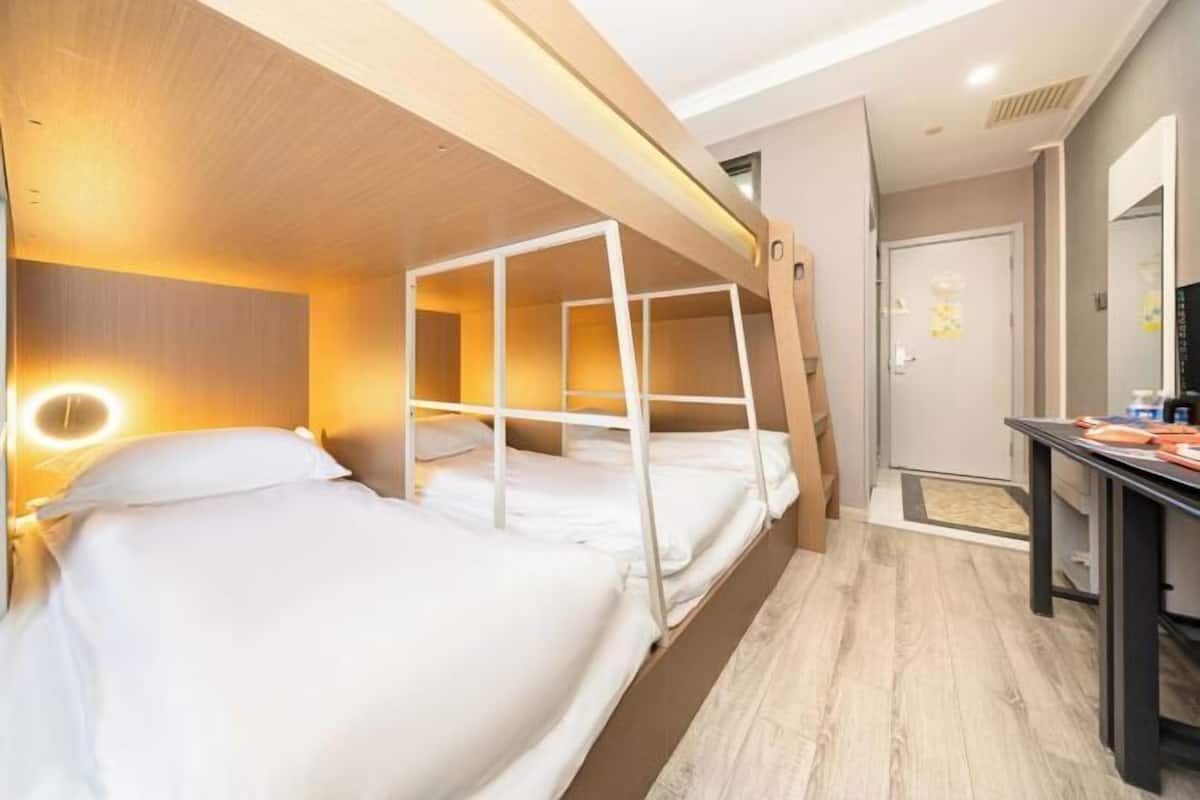 A bunk bed room with a desk and a mirror.