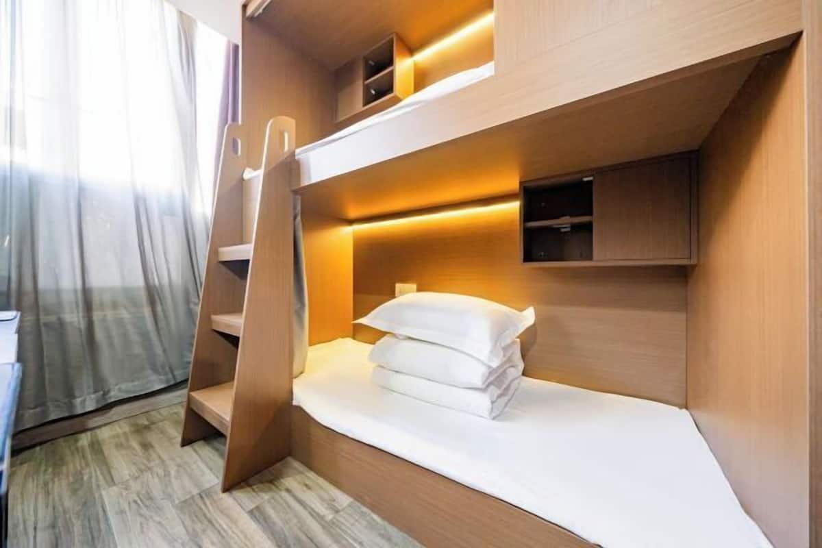 A bunk bed room with a wooden ladder, a small shelf, and a bedside table.