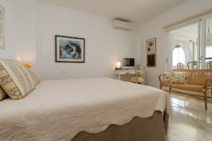 A bedroom with a bed, a desk, a chair, and a wicker sofa. - Mairena 23 - Sea view apartment (Ojen)