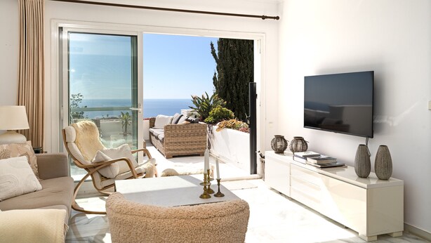 En moderne stue med balkon, fladskærms-tv og havudsigt.