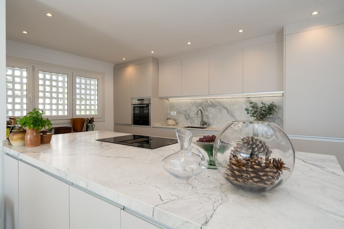 A modern kitchen with a marble countertop, a built-in oven, and a large window with a view.