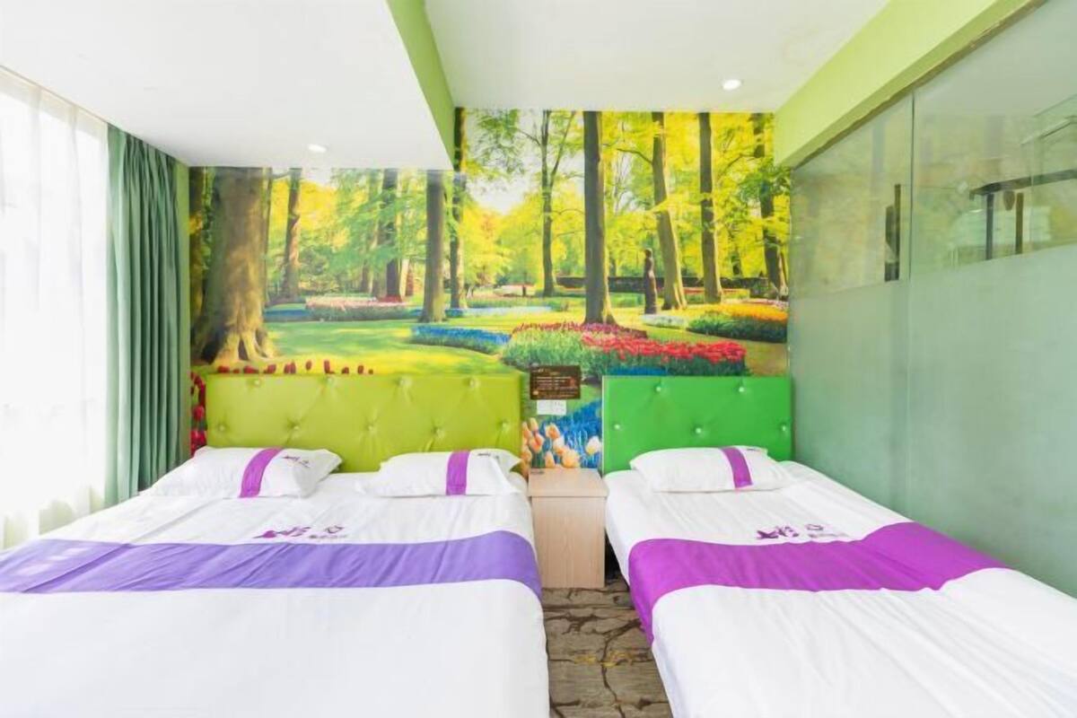 Ein Zimmer mit zwei Betten, einem Wandgemälde eines Waldes und einer grünen Wand.