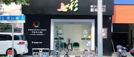 A hotel entrance with a black facade, a signboard, and bicycles parked outside.