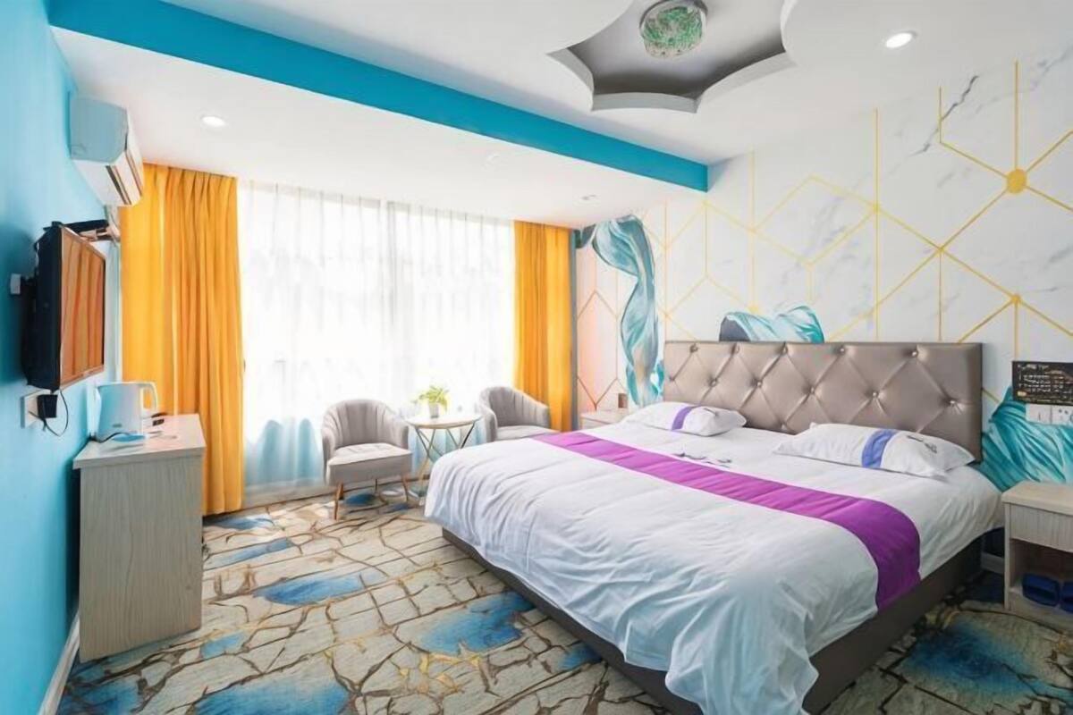 Ein Hotelzimmer mit Bett, Schreibtisch, Stuhl, kleinem Tisch und Fernseher.
