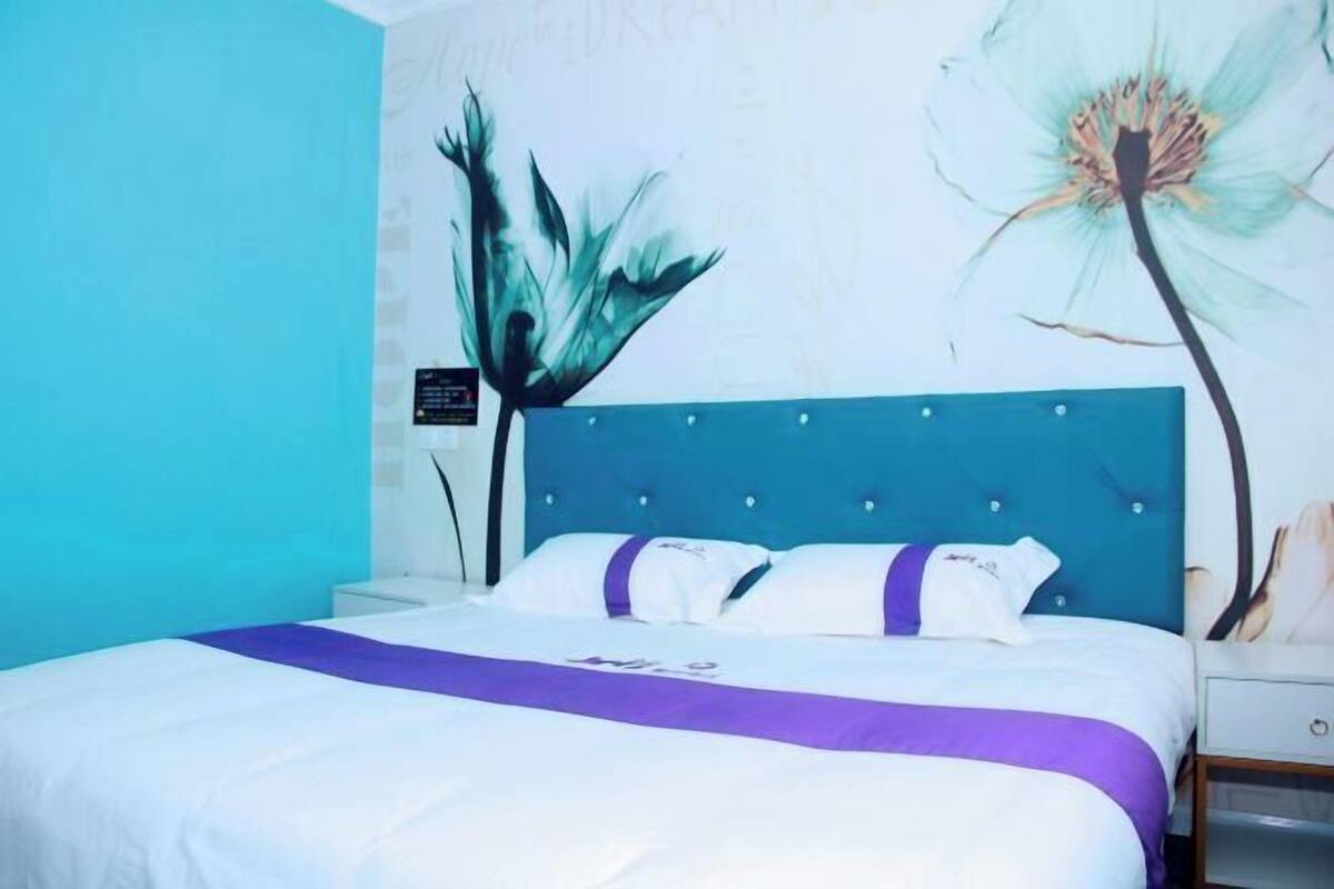 Ein Bett mit blauem Kopfteil, weißer Bettwäsche und violetten Akzenten.