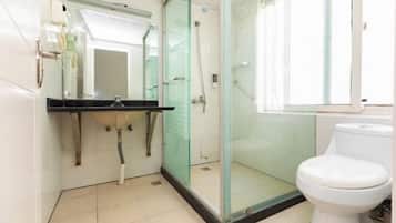 A bathroom with a glass-enclosed shower, a white toilet, and a sink with a mirror above it.