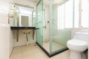 A bathroom with a glass-enclosed shower, a white toilet, and a sink with a mirror above it. - Colorful Art Hotel Shanghai (Shanghai)