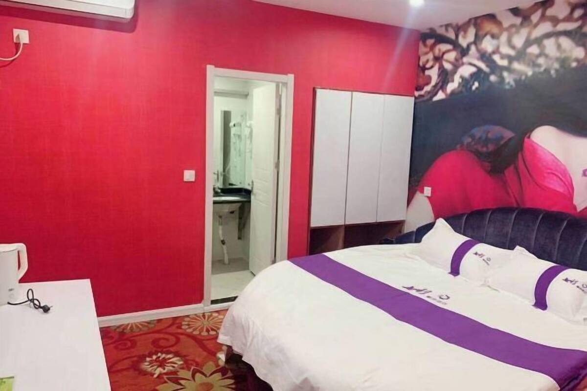 Ein Schlafzimmer mit einem Bett, einem Kleiderschrank, einem Spiegel und einer Tür zu einem Badezimmer.