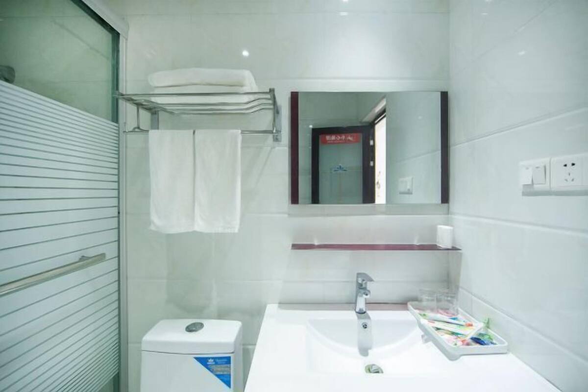 A modern bathroom with a white sink, a mirror, a towel rack, and a toilet.