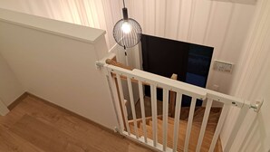 A wooden staircase with a white railing, a hanging light fixture, and a dark-colored wall with a window.