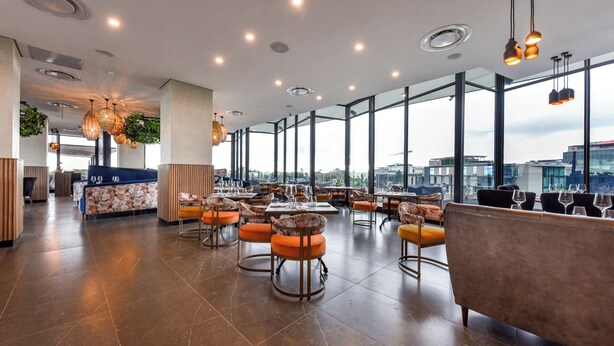 A spacious restaurant with high ceilings, large windows, and modern lighting fixtures.
