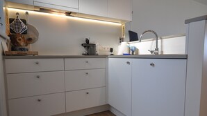 A modern kitchen with white cabinets, a wooden countertop, and a stainless steel sink. - Apartment in Belgium Near Seafront & Casino (Knokke-Heist)