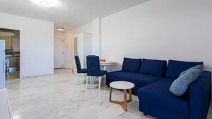 A modern living room with a blue sofa, a small round table, and two matching chairs.