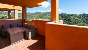 A balcony with a sofa and table, overlooking a mountainous landscape.