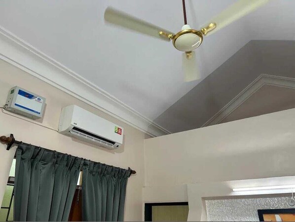 Un ventilador de techo, un equipo de aire acondicionado y una cortina.