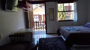 Une chambre à coucher avec un lit, un bureau, une chaise, une télévision et une fenêtre.