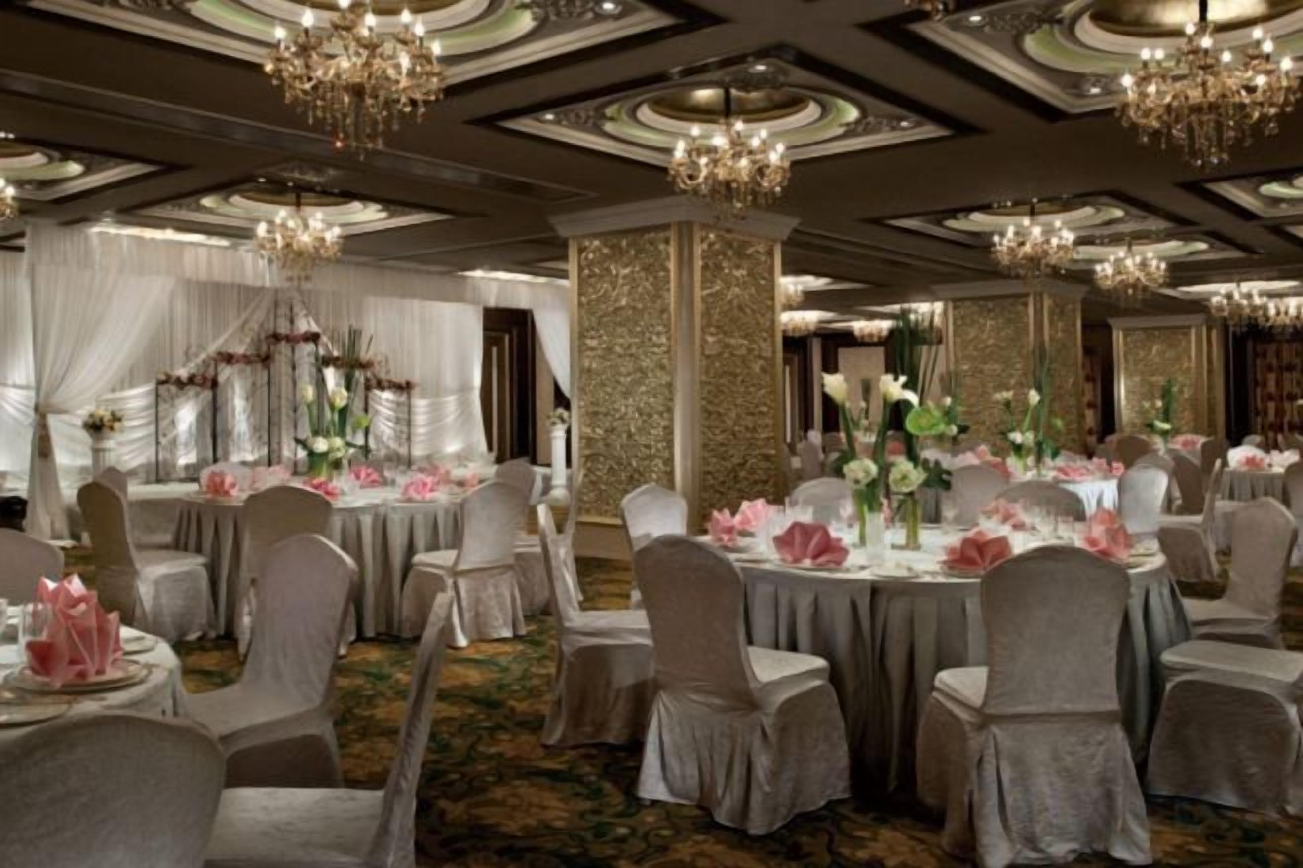Un salón de banquetes con mesas redondas, sillas y candelabros.