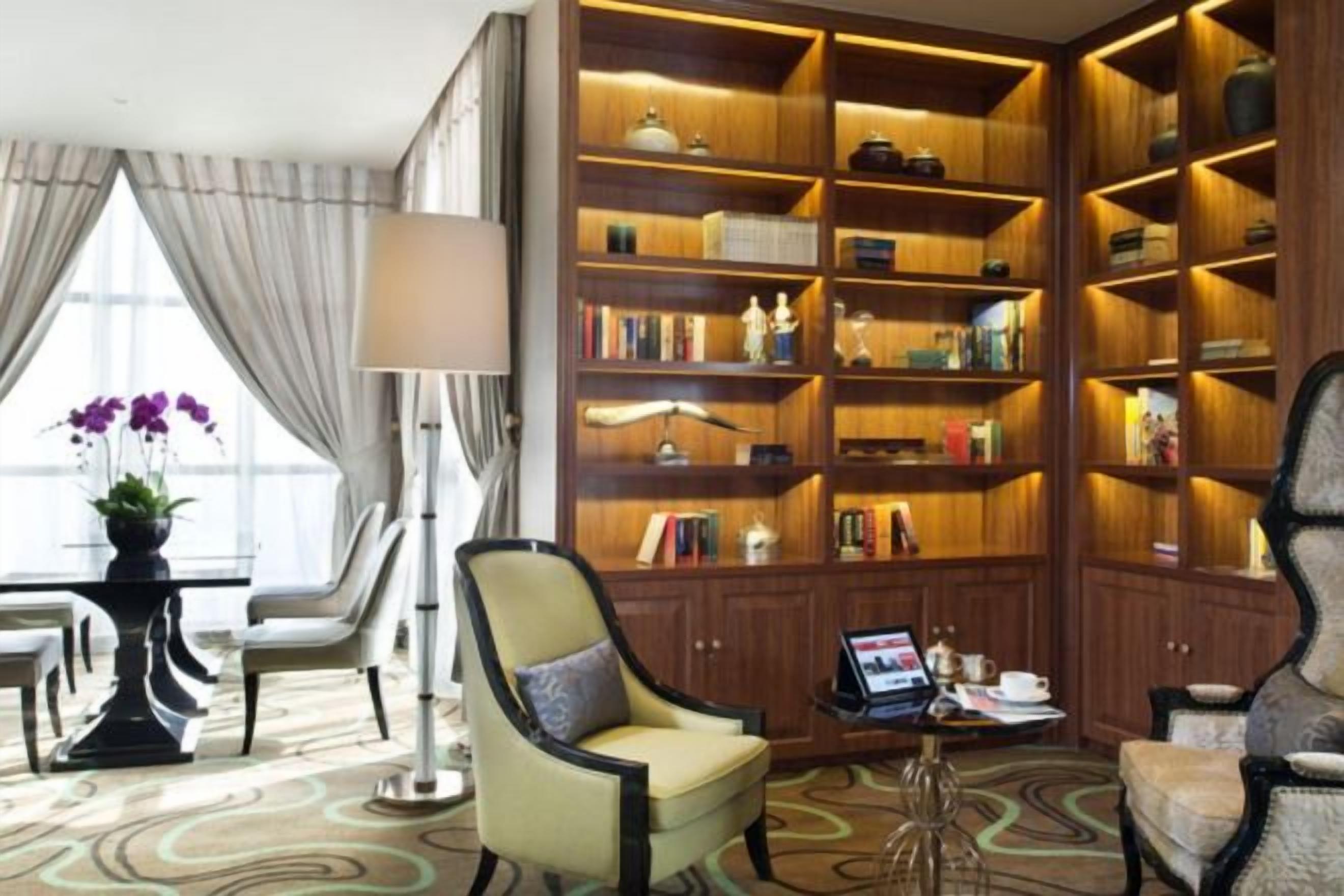 Una habitación luminosa con una amplia estantería de madera, asientos cómodos y una pequeña mesa con lámpara.