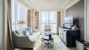 A hotel room with a sofa, a chair, a coffee table, a TV, and a minibar. - Ramada Plaza by Wyndham Tian Lu Hotel Wuhan (Wuhan)