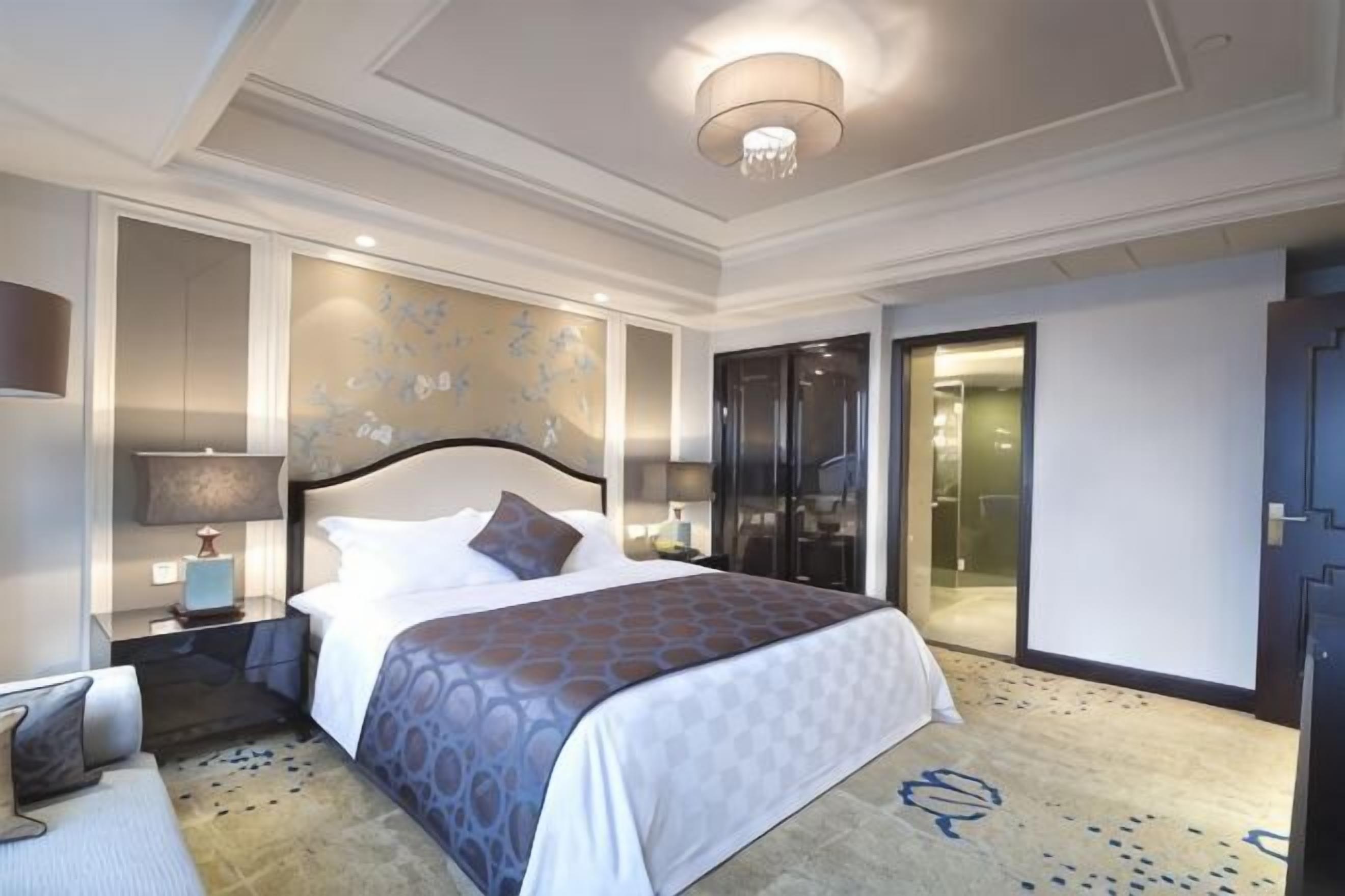 A modern hotel room with a large bed, bedside tables, a desk, and a walk-in closet.