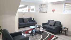 A modern living room with two sofas, a coffee table, and a small side table. - Luxurious 2 BDRMS Basement Legal Suite (Edmonton)