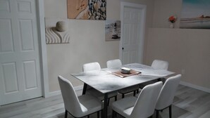 A dining area with a marble table and six white chairs. - Luxurious 2 BDRMS Basement Legal Suite (Edmonton)