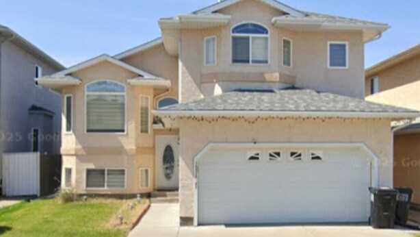A two-story house with a garage, a driveway, and a lawn. - Luxurious 2 BDRMS Basement Legal Suite (Edmonton)