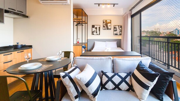 Una habitación de hotel compacta con cama, comedor y balcón con vistas.