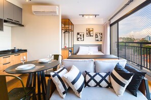 Una habitación de hotel compacta con cama, comedor y balcón con vistas.