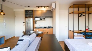 Una habitación de hotel compacta con kitchenette, comedor y cama.