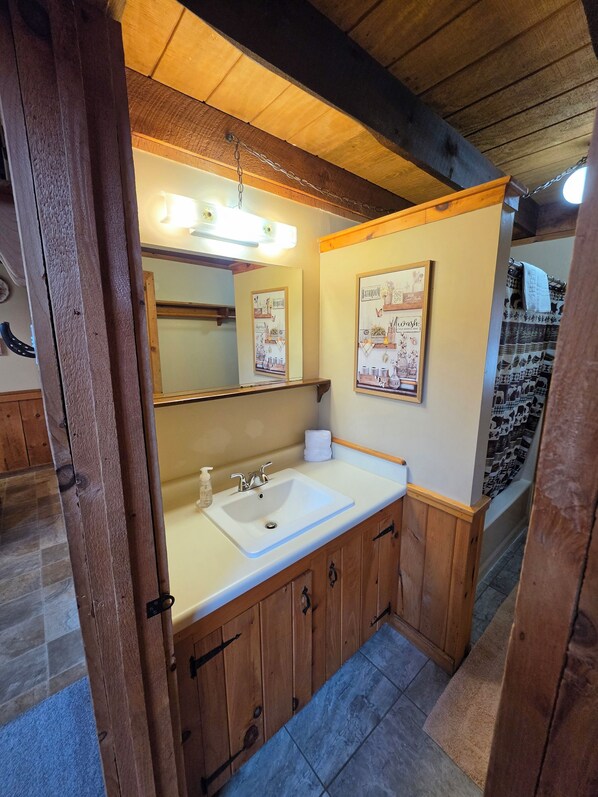 A bathroom with a wooden vanity, a sink, a mirror, and a shower curtain.