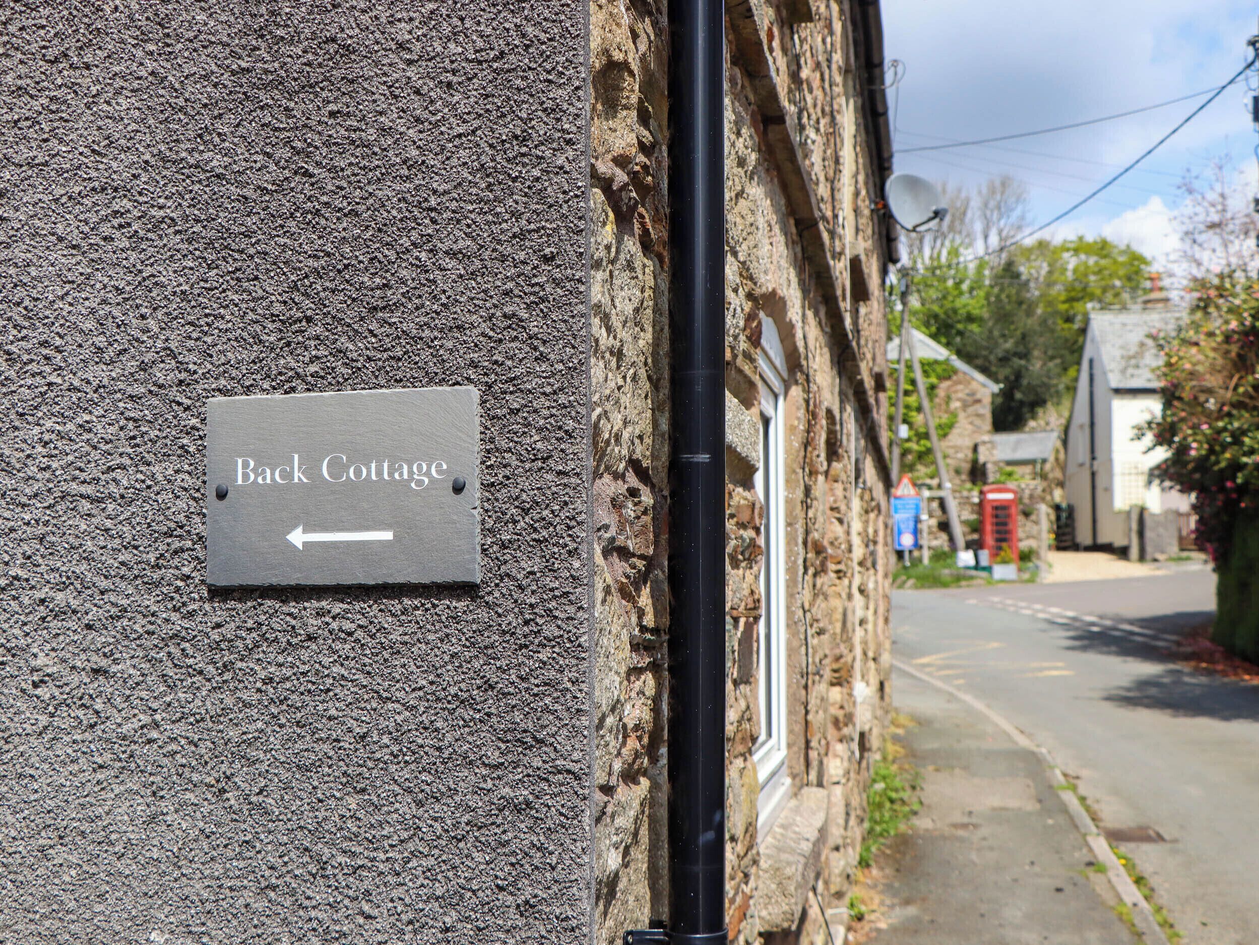 A sign indicating 'Back Cottage' with a directional arrow.