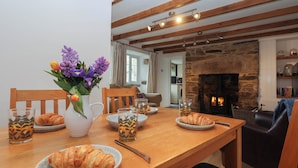 Un comedor con una mesa de madera dispuesta para el desayuno, con croissants y un jarrón de flores.