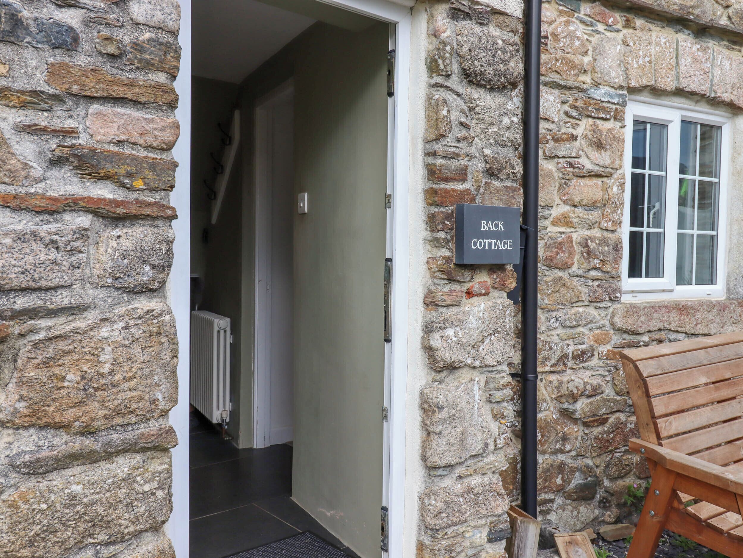 A stone cottage entrance with a sign reading "BACK COTTAGE".