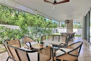 Une terrasse extérieure avec des meubles en osier et un ventilateur de plafond.