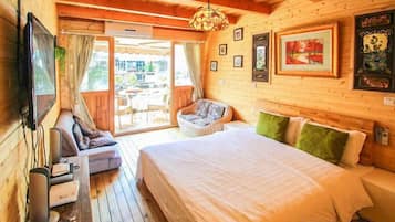 Una habitación de madera con una cama, una silla, un televisor y una ventana.