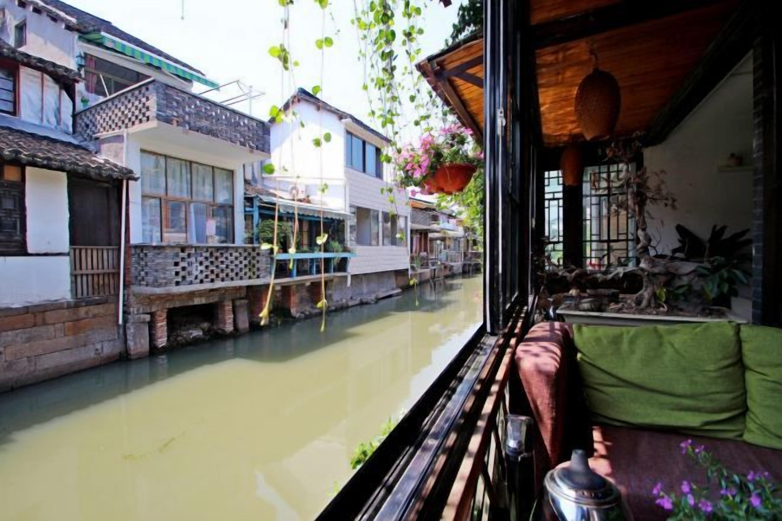 Un edificio tradicional con balcón que da a un canal, con plantas colgantes y vistas al agua.