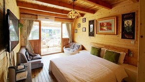 A wooden cabin bedroom with a bed, a seating area, and a television. - Shanghai Jiaoli Xiaoyan Inn (Zhujiajiao Scenic Area Ancient Town) (Shanghai)
