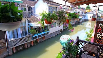 Un canal estrecho bordeado por edificios tradicionales con macetas colgantes y un banco de madera.