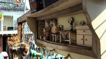 Un espacio pequeño y cerrado con un estante de madera que contiene varios objetos, como un reloj, un florero y una mesita.