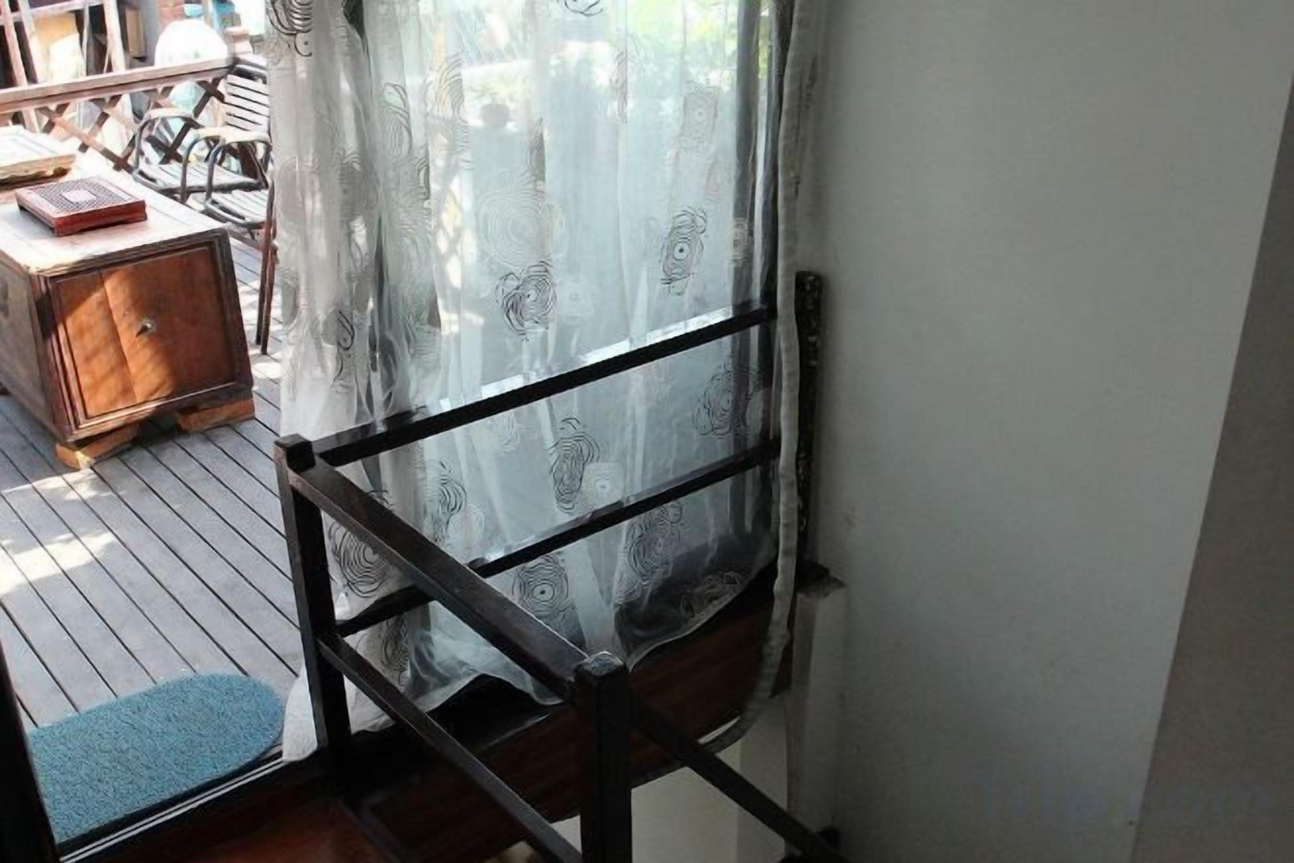 Una habitación con una silla de madera, una mesita y una cortina.