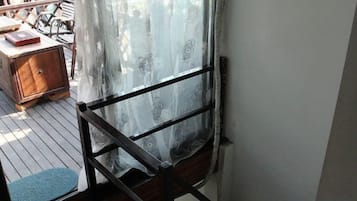 Una habitación con una silla de madera, una mesita y una cortina.