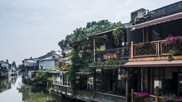 A traditional canal house with wooden balconies and hanging plants. - Shanghai Jiaoli Xiaoyan Inn (Zhujiajiao Scenic Area Ancient Town) (Shanghai)