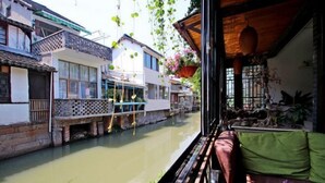 A traditional building with a wooden balcony overlooking a calm river. - Shanghai Jiaoli Xiaoyan Inn (Zhujiajiao Scenic Area Ancient Town) (Shanghai)