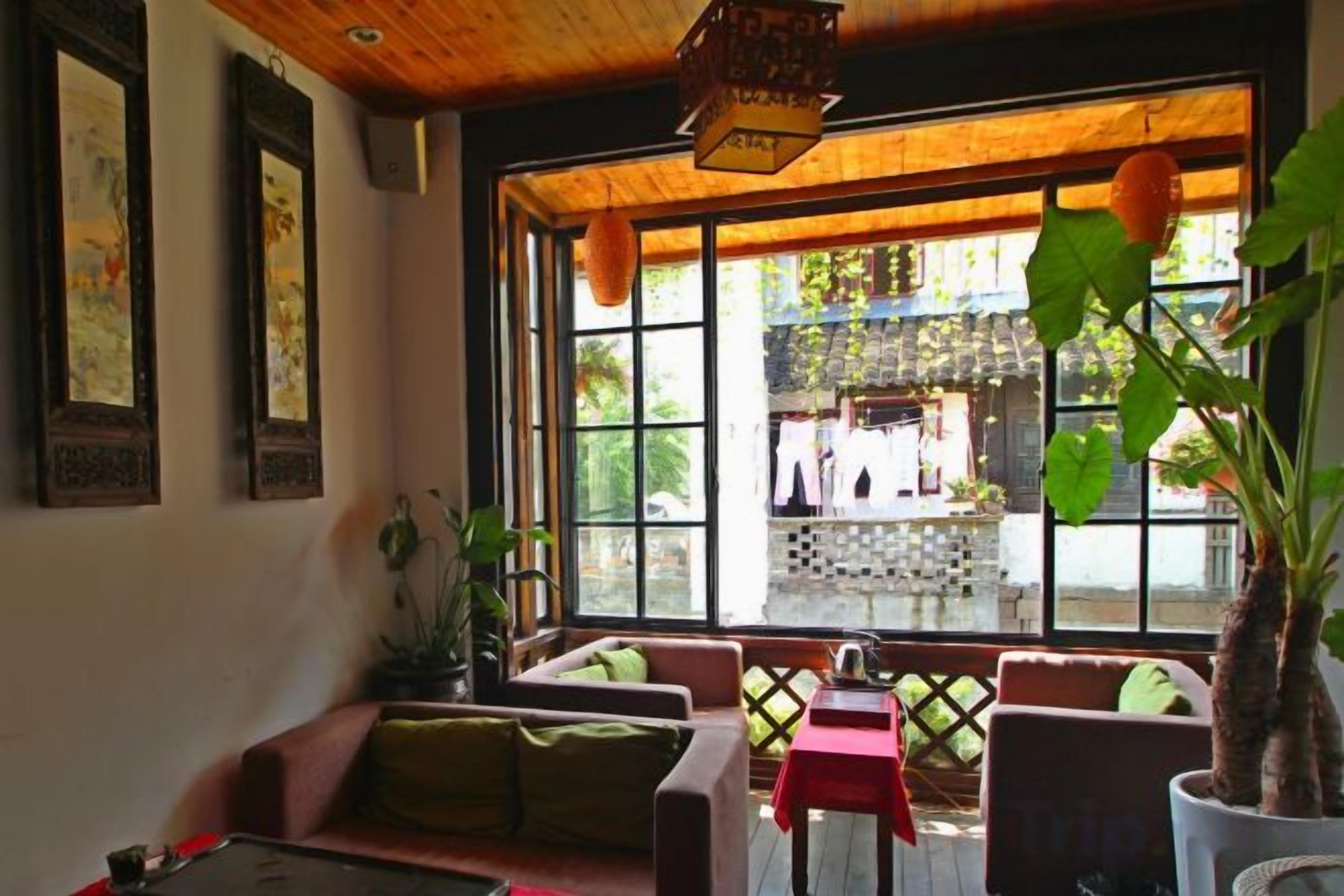 A room with a large window, a sofa, a table, and a potted plant.