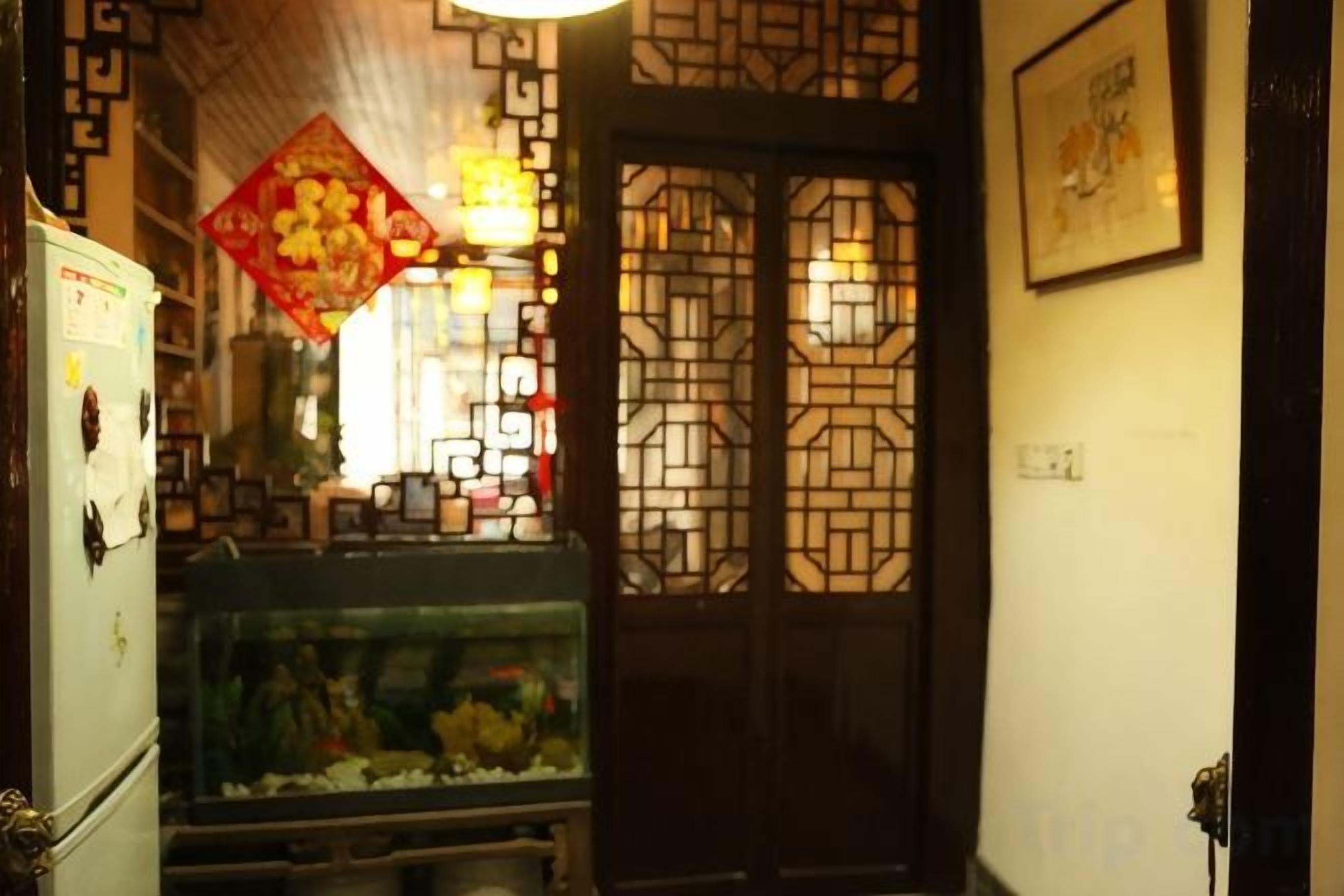 A traditional interior with a decorative door, a fish tank, and a refrigerator.