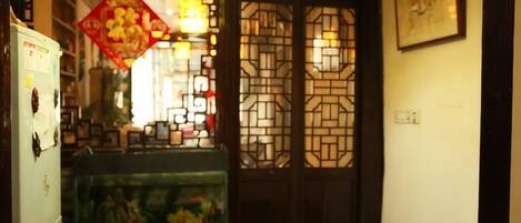 A traditional interior with a decorative door, a fish tank, and a refrigerator.