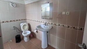 A bathroom with a toilet, sink, and mirror.
